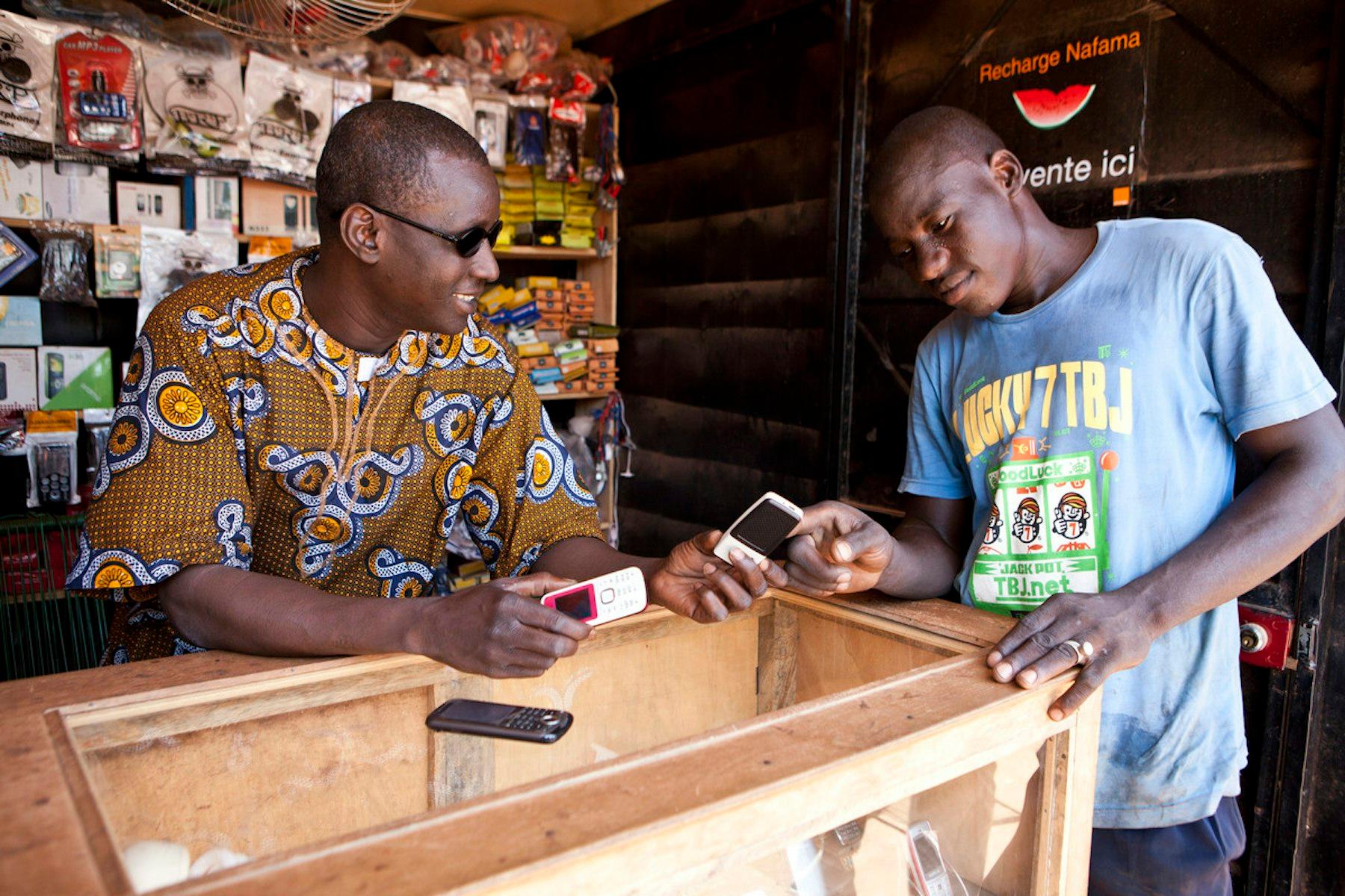 A man stands at the table of a small kiosk, engaging in a digital financial transaction.