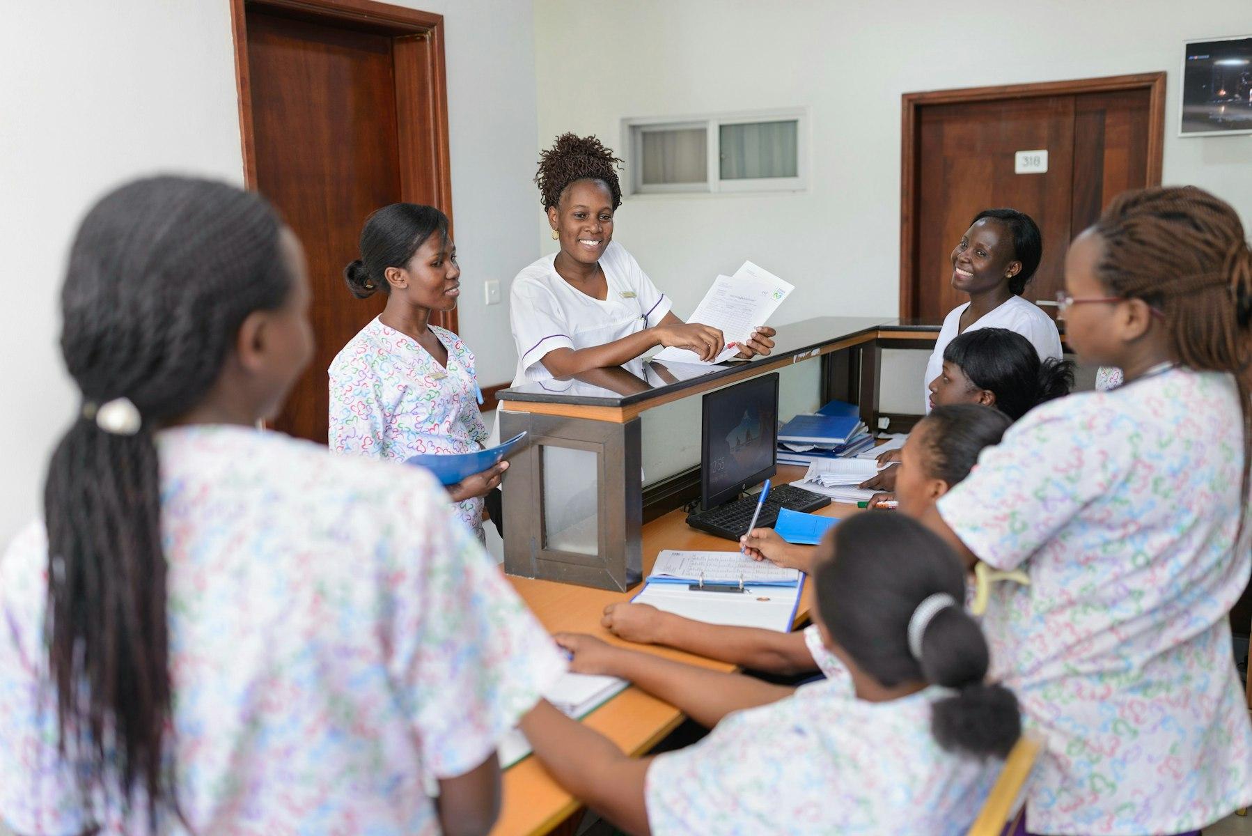 Medical staff confer around a hospital reception desk.