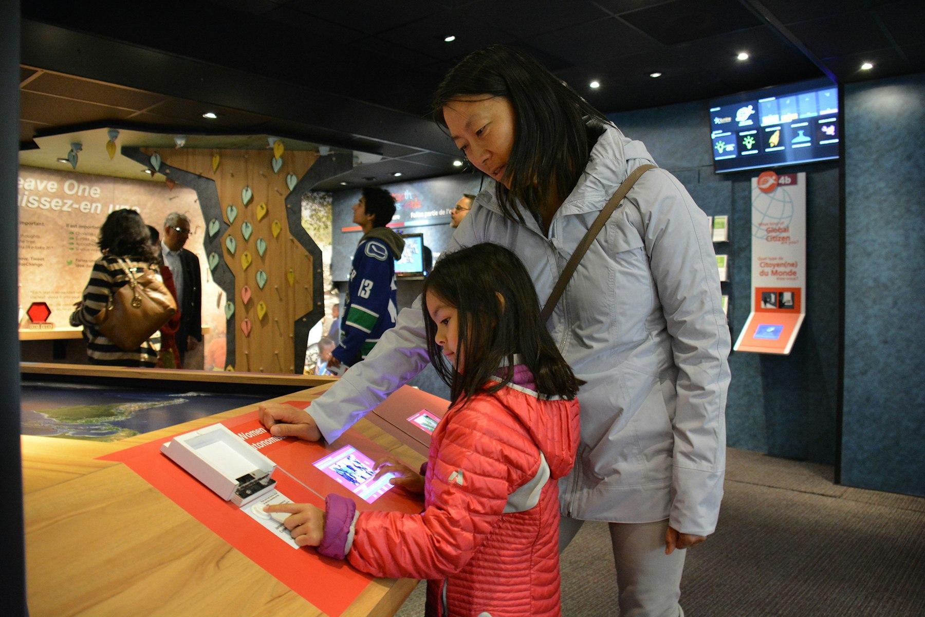 A child and her mother look at an interactive exhibit within a truck.