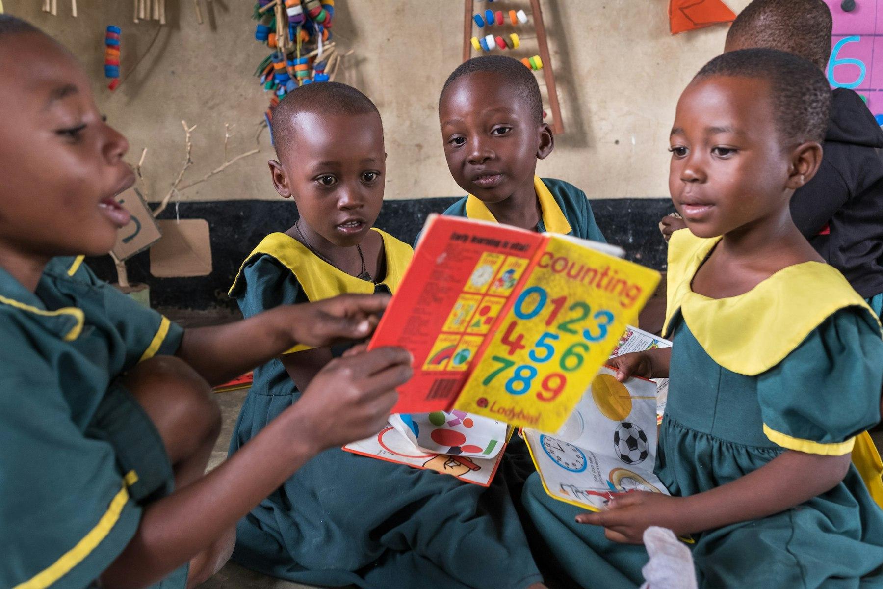 Four children in green uniforms read from a book titled 'Counting'.