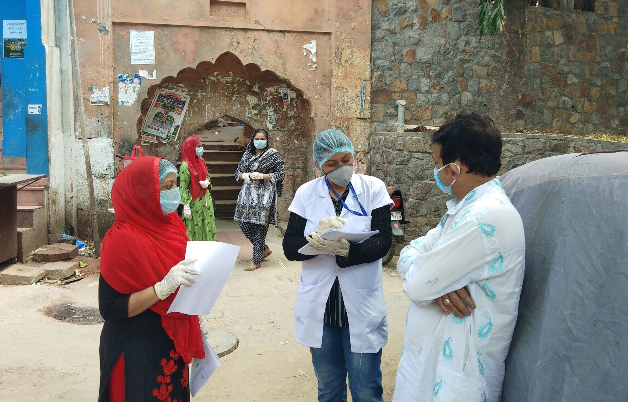 Women with COVID masks make notes on a questionnaire.
