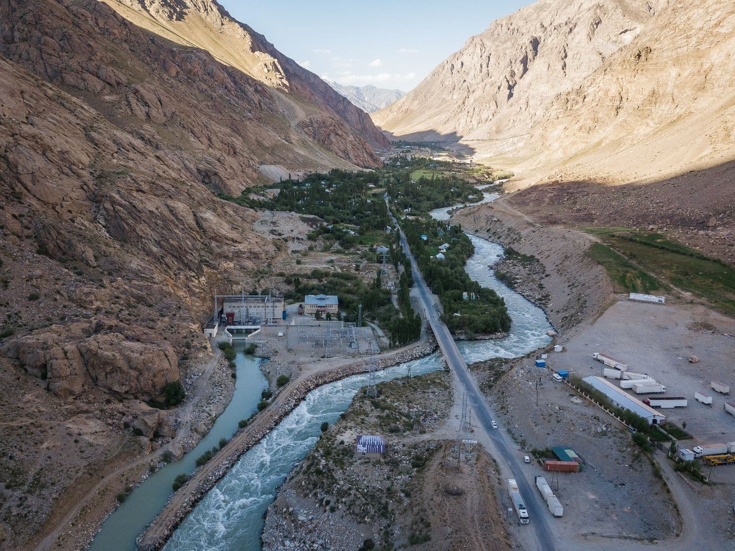 Aerial view of the Khorog 1 Hydropower Plant in a river valley, with a road alongside.
