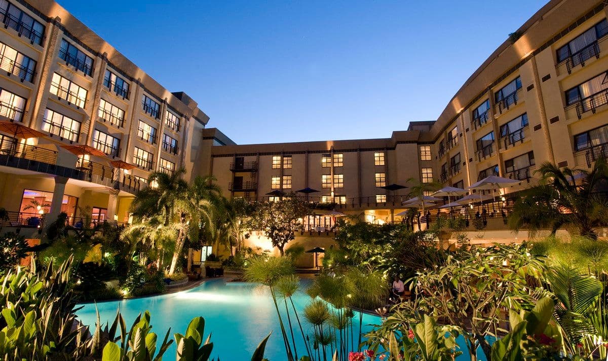 Kigali Serena Hotel, with plants in front of a lit pool in front of the building.