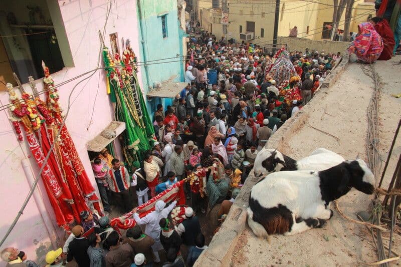 View over a crowded street with goats tethered on a roof.