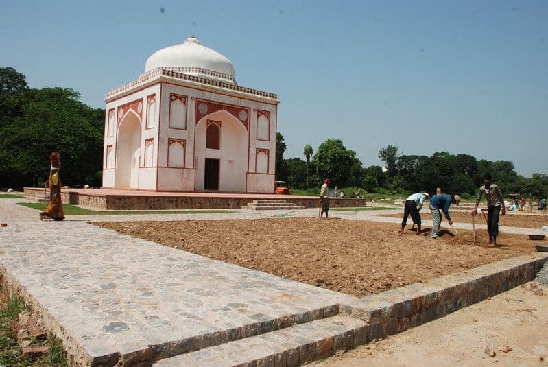 People arrange soil in a square of earth outside the Sunder Burj.